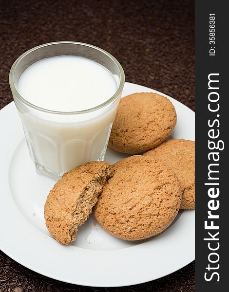 Glass of milk and oat cookies on a plate, close-up