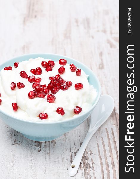 Homemade yogurt with pomegranate seeds, vertical, close-up