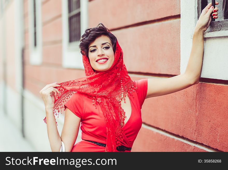 Portrait of a pretty woman, vintage style, in urban background, wearing a red dress. Portrait of a pretty woman, vintage style, in urban background, wearing a red dress