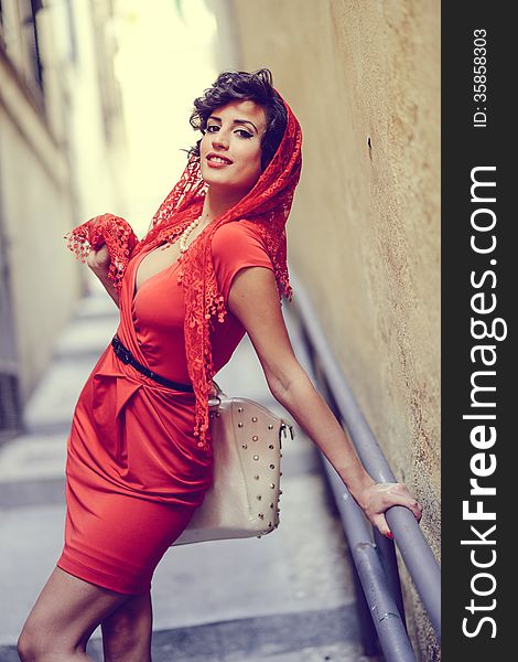 Portrait of a pretty woman, vintage style, in urban background, wearing a red dress. Portrait of a pretty woman, vintage style, in urban background, wearing a red dress