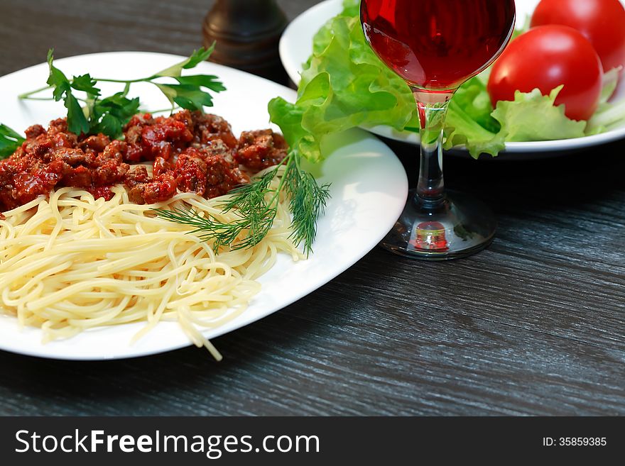 Closeup of plate with pasta near red wine and vegetables. Closeup of plate with pasta near red wine and vegetables