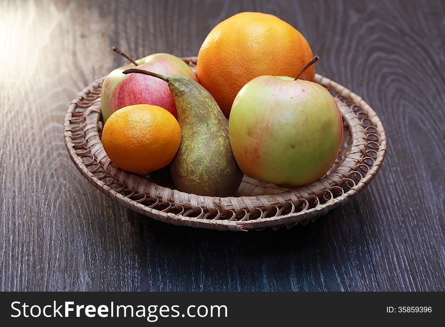 Set of various fruits in wicker basket on wooden table. Set of various fruits in wicker basket on wooden table
