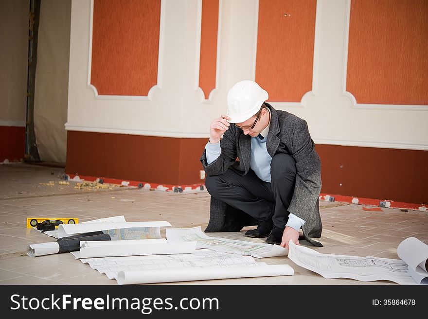 Architect or engineer in the white hard hat with the blueprint. Reconstruction interior. Architect or engineer in the white hard hat with the blueprint. Reconstruction interior.