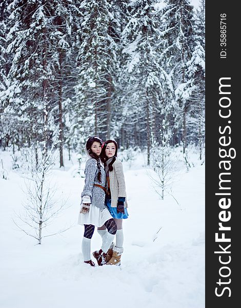 Fashion women in warm sweaters on white snow forest background