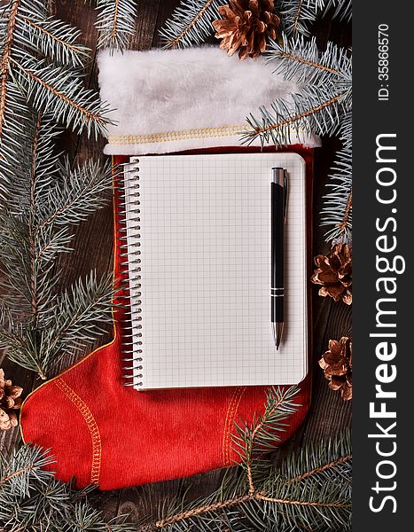 New Year`s composition of a red Christmas sock, fir branches and notebook. New Year`s composition of a red Christmas sock, fir branches and notebook