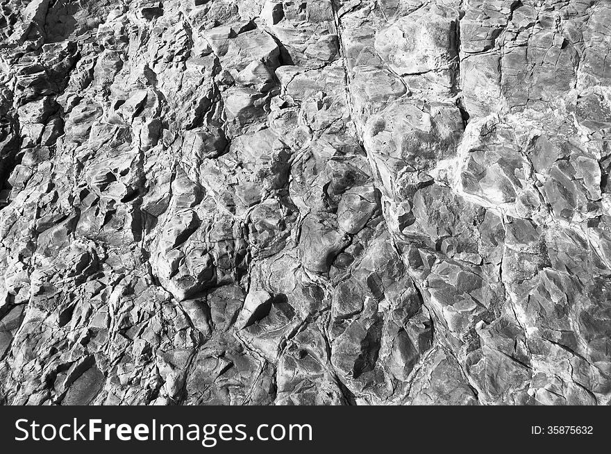 Black and white image of the surface designated rock in the foreground, cracked, chipped, deepening. Black and white image of the surface designated rock in the foreground, cracked, chipped, deepening