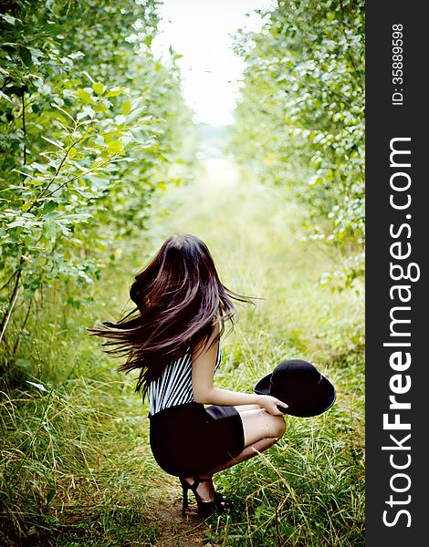 Fashionable woman waving her hair in green forest