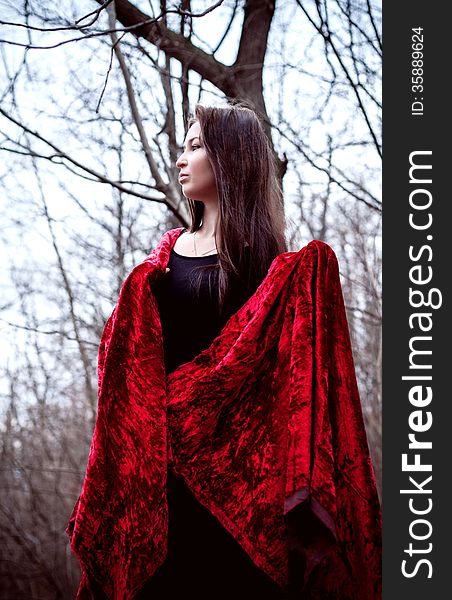 Woman In Black Dress With Red Fabric In Cold Dark Forest