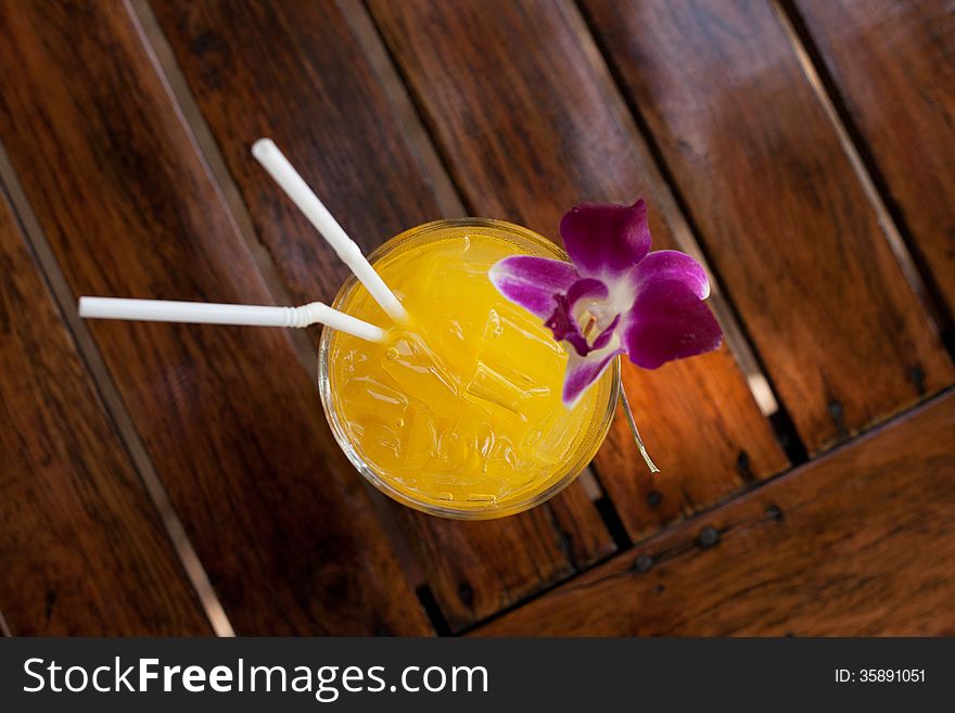 Yellow fruit coctail in a glass, with flower and straws. Yellow fruit coctail in a glass, with flower and straws