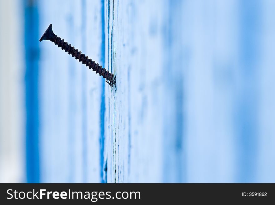 Old screw on a blue painted wall