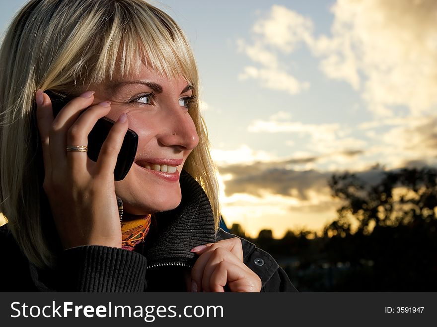 Yong girl talks on the phone outdoors. Yong girl talks on the phone outdoors