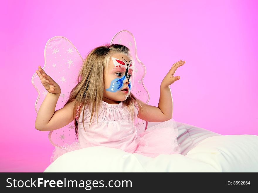 A studio shot of little girl dressed as butterfly on pink background. A studio shot of little girl dressed as butterfly on pink background