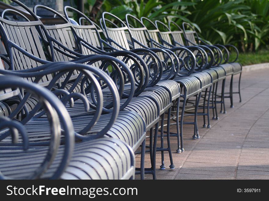 A row of chairs in a park like setting.