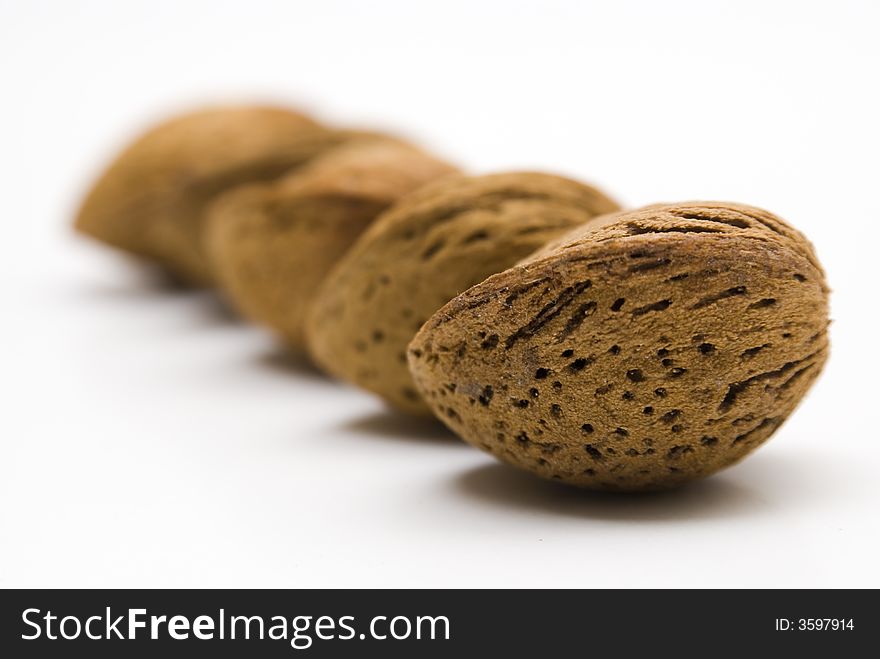 Four almonds aligned on a white table