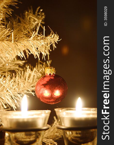 Composition of two burning candles underneath a silver fir branch with red christmas-ball. Composition of two burning candles underneath a silver fir branch with red christmas-ball