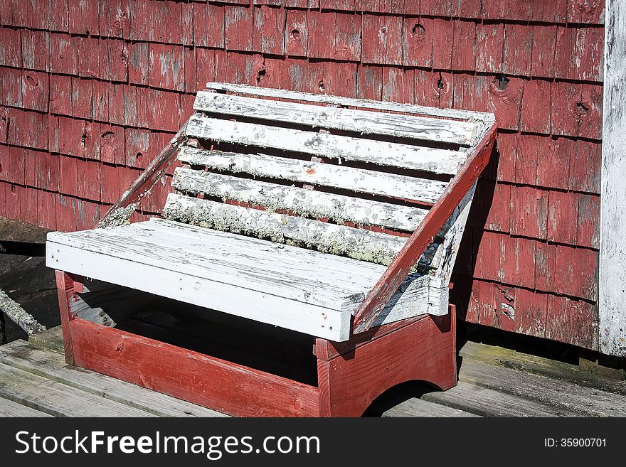 Old wooden bench against a red building. Old wooden bench against a red building