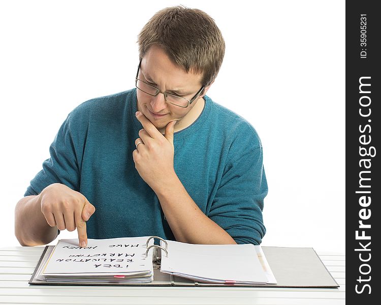 One man sitting at a desk reading paperwork with a sceptical look. One man sitting at a desk reading paperwork with a sceptical look