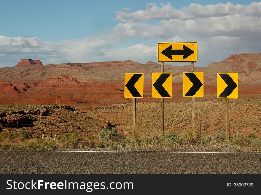 Bright yellow directional traffic arrow signs along desert highway. Bright yellow directional traffic arrow signs along desert highway.