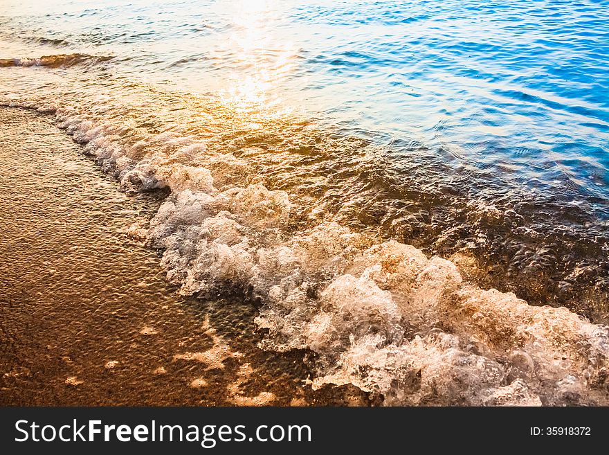 Soft sea ocean waves wash over golden sand background. Sunset, sunrise. Soft sea ocean waves wash over golden sand background. Sunset, sunrise