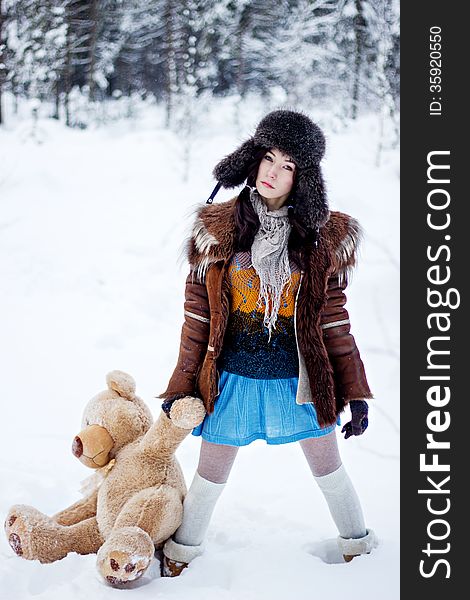 Woman in fur coat and ushanka with bear on white snow winter background