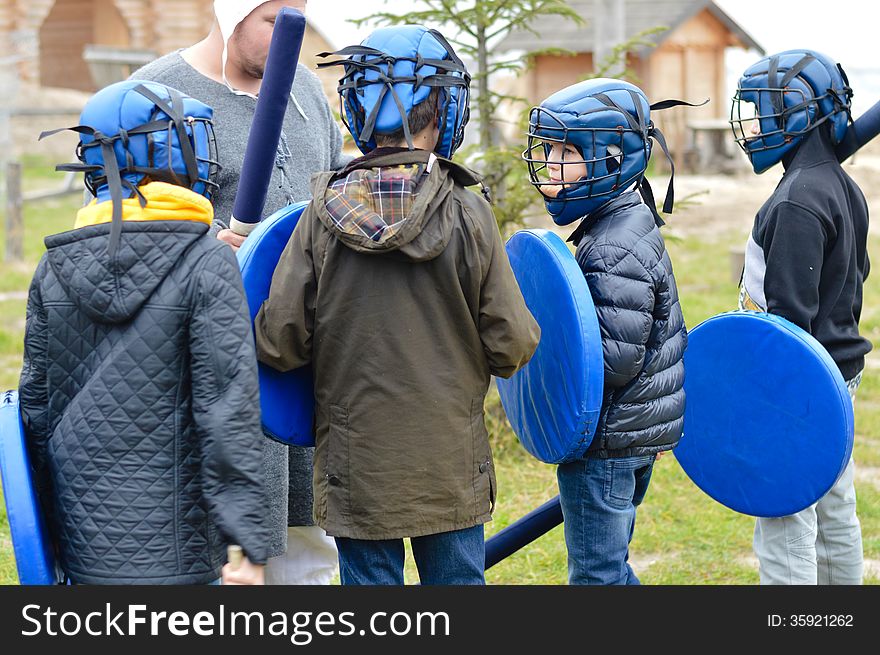 Group of school boys getting ready for fight training in rubber armor and helmets outdoors