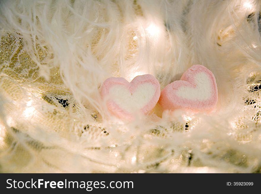 Sweet heart marshmallow on white feathers and lights