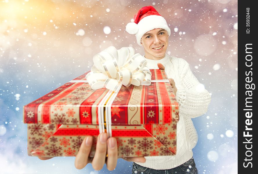 Young man in Santa Claus hat holding a gift box