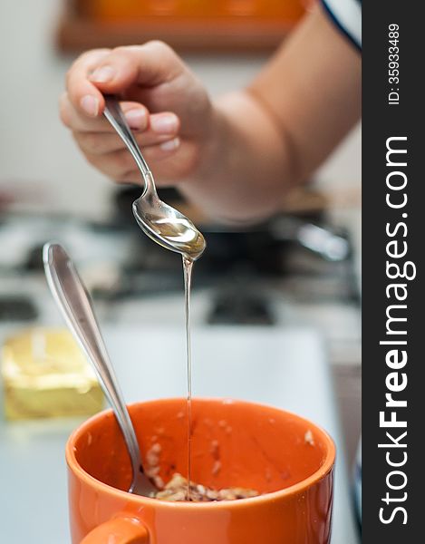 Woman hand adding honey in banana puree. Woman hand adding honey in banana puree