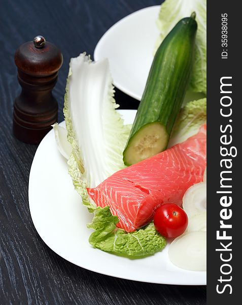 Closeup of filleted salmon on plate near various vegetables. Closeup of filleted salmon on plate near various vegetables