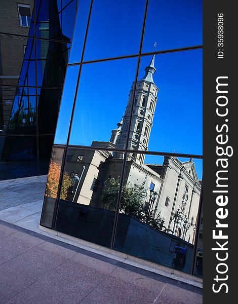 Modern glass wall with reflection of old church against blue sky. Modern glass wall with reflection of old church against blue sky