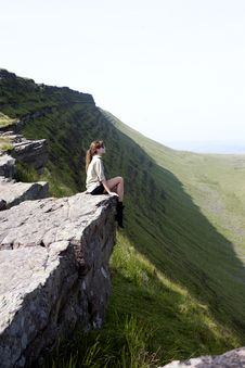 GIRL SITTING ON THE TOP OF A CLIFF Royalty Free Stock Images
