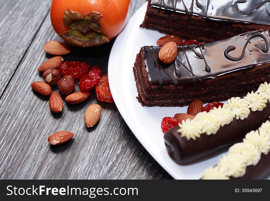 Dessert. Set of chocolate cakes and fruits on white plate. Dessert. Set of chocolate cakes and fruits on white plate