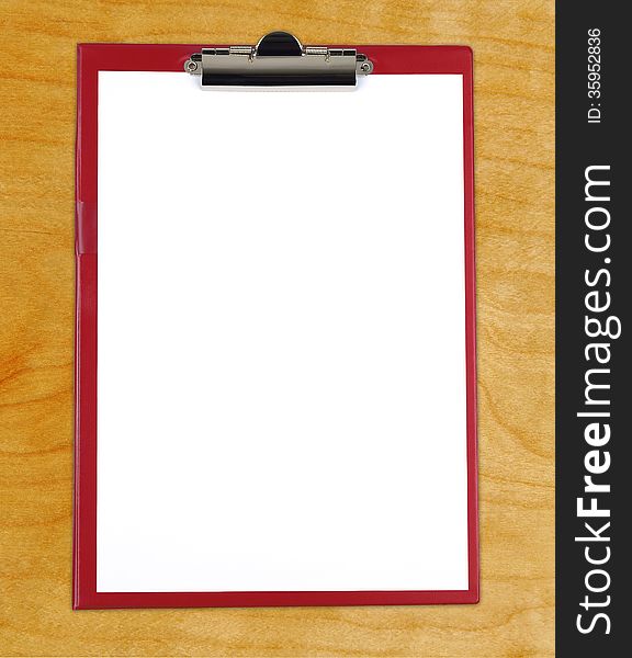 Clipboard with blank white paper on wooden desk.