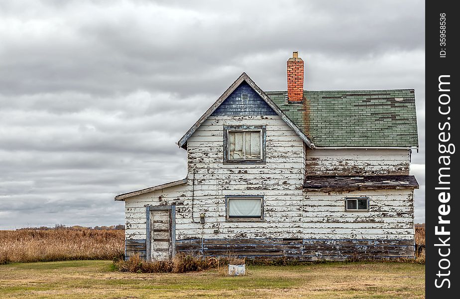 Old abandoned blue and white house.the paint is peeling off the wood siding. Old abandoned blue and white house.the paint is peeling off the wood siding