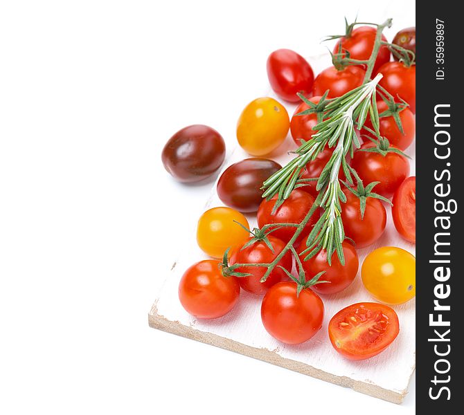 Colorful cherry tomatoes and rosemary on a white wooden board, isolated on white