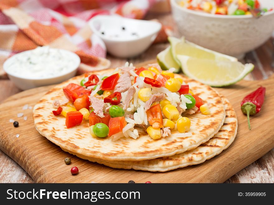 Colorful vegetable salad with tuna and cream sauce on a wheat tortilla, close-up. Colorful vegetable salad with tuna and cream sauce on a wheat tortilla, close-up