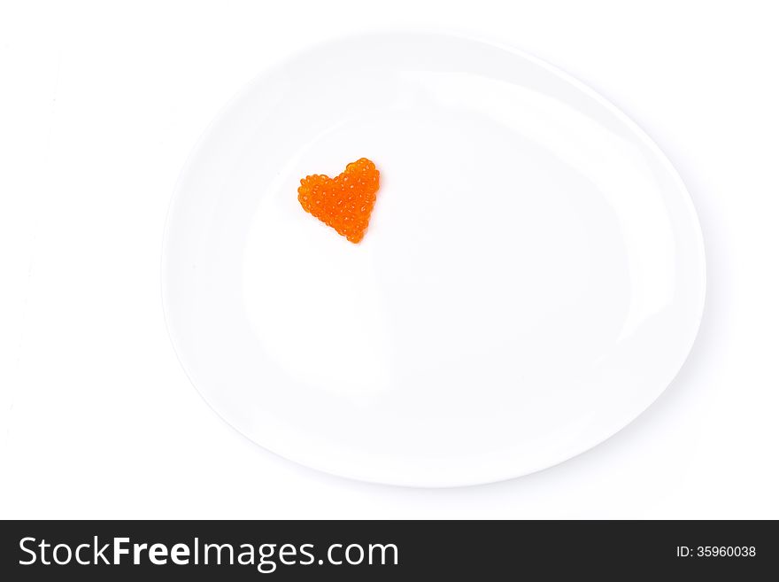 Heart of red caviar on a plate, isolated on white