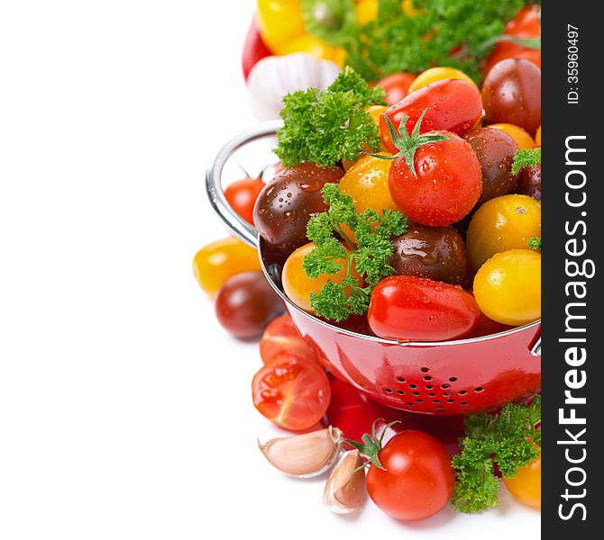 Assorted cherry tomatoes in a colander and fresh herbs, isolated on white