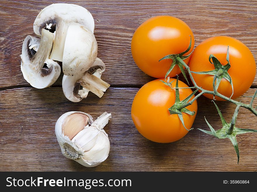 Fresh tomatoes, garlic and mushrooms on vintage wooden table. Fresh tomatoes, garlic and mushrooms on vintage wooden table