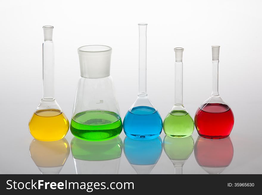 Laboratory glassware with liquids of different colors, isolated on white background