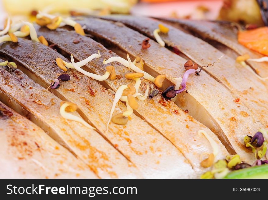 Oriental cuisine, sprouted soybeans over fried fish, macro closeup