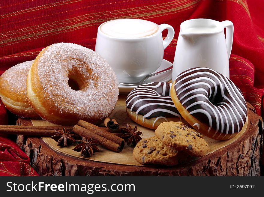 Donut with chocolate and sugar on wooden stump with cinnamon and background with red cloth. Donut with chocolate and sugar on wooden stump with cinnamon and background with red cloth