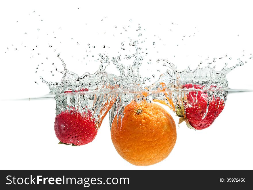 Orange and strawberries falling into the water. Orange and strawberries falling into the water