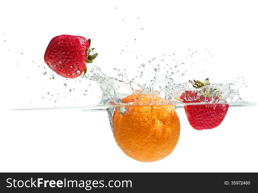 Orange and strawberries falling into the water. Orange and strawberries falling into the water