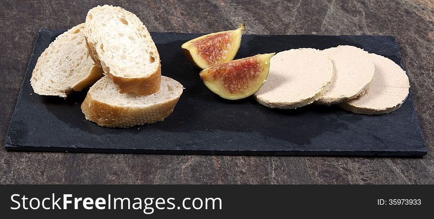 A slate plate of fois gras, bread and fig