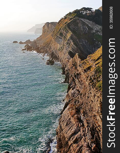 The Jurassic Coast showing rock strata, near West Lulworth, Purbeck, Dorset The Jurassic Coast is a World Heritage Site on the south coast of England. It reaches from Devon in the west to Old Harry Rocks near Swanage, Dorset, to the East. The Jurassic Coast showing rock strata, near West Lulworth, Purbeck, Dorset The Jurassic Coast is a World Heritage Site on the south coast of England. It reaches from Devon in the west to Old Harry Rocks near Swanage, Dorset, to the East