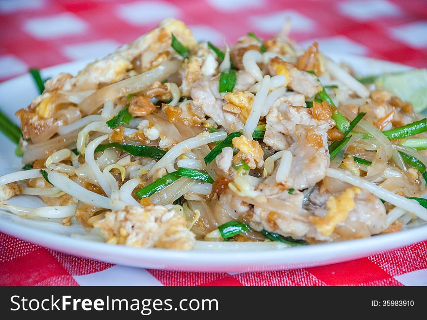 A delicious plate of Pad Thai with shrimp and chicken garnished with cilantro and lime.