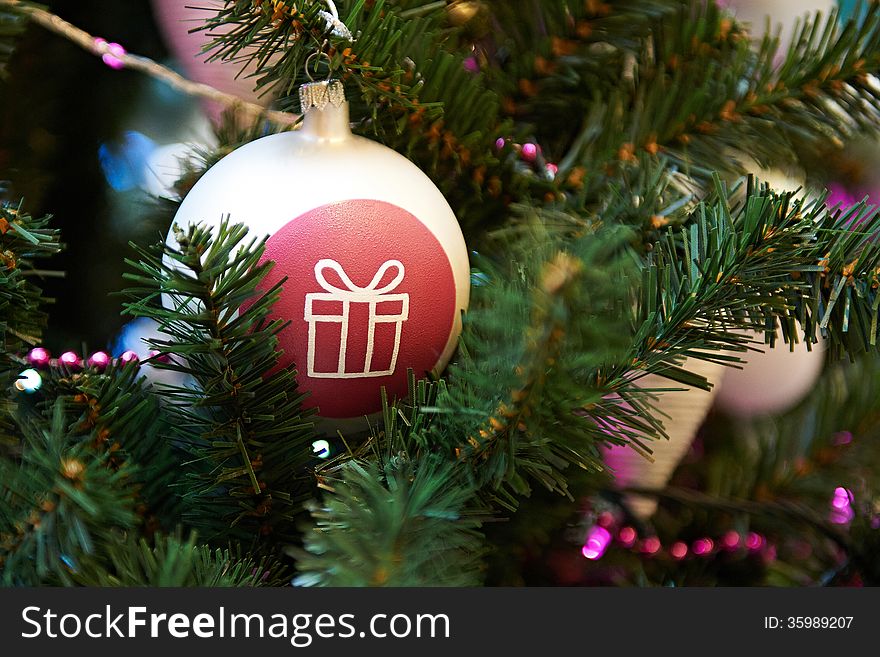 Christmas ball with painted gift on the Christmas Tree