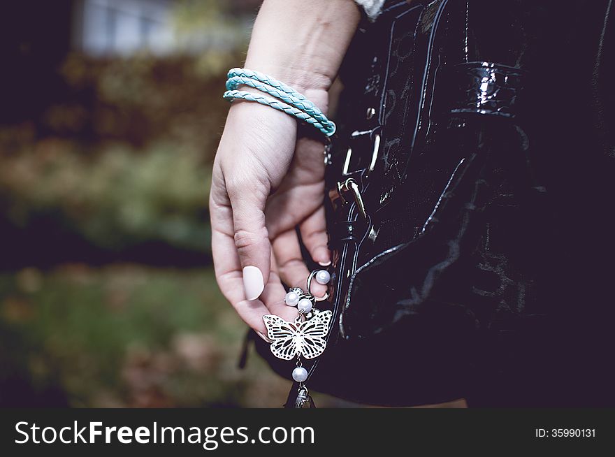 Young woman with silver jewelry on hand with black bag. Young woman with silver jewelry on hand with black bag