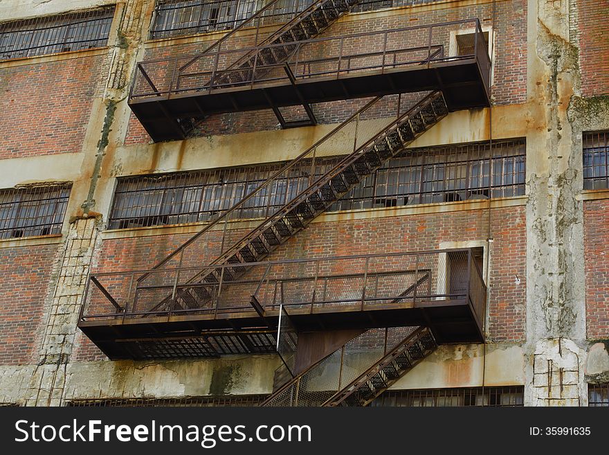 Rusty Old Fire Escape Stairs on Warehouse Brick Wall.